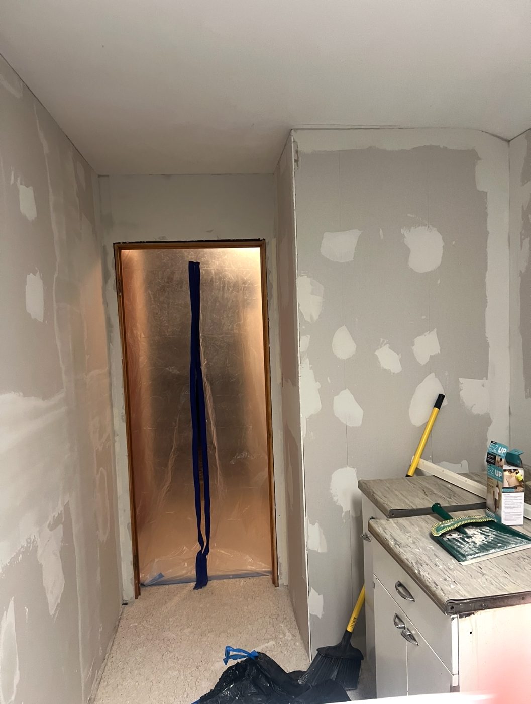 Masked doorway and patched drywall prepped for painting