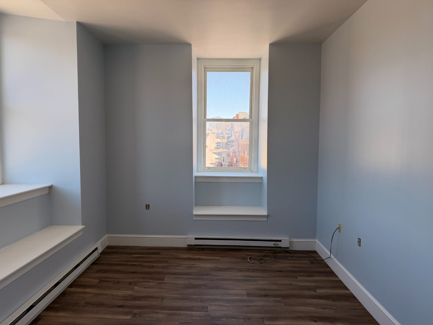 Newly painted blue bedroom with bay window and white baseboards