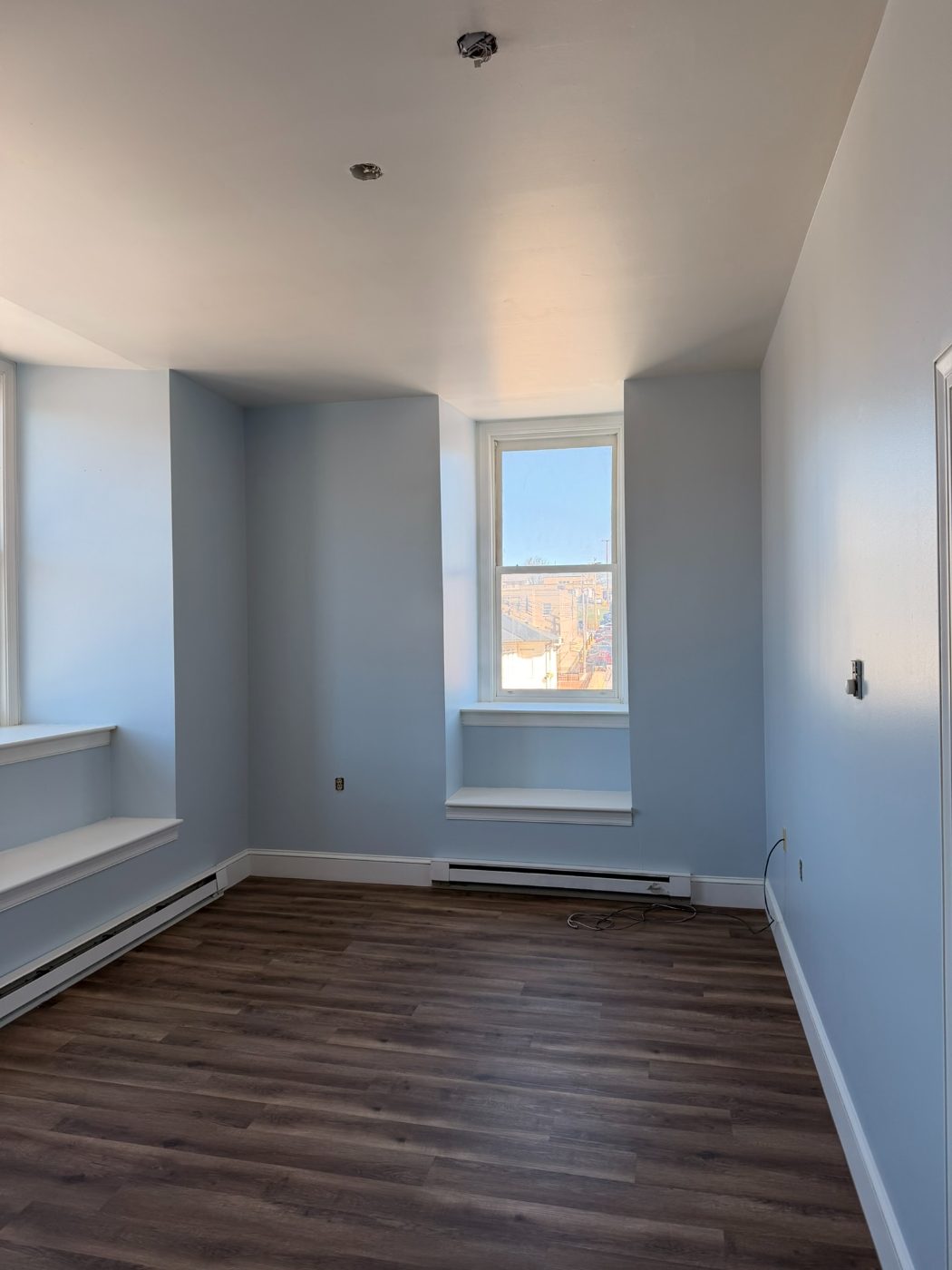 Bright blue painted bedroom with white ceiling and large sunny window