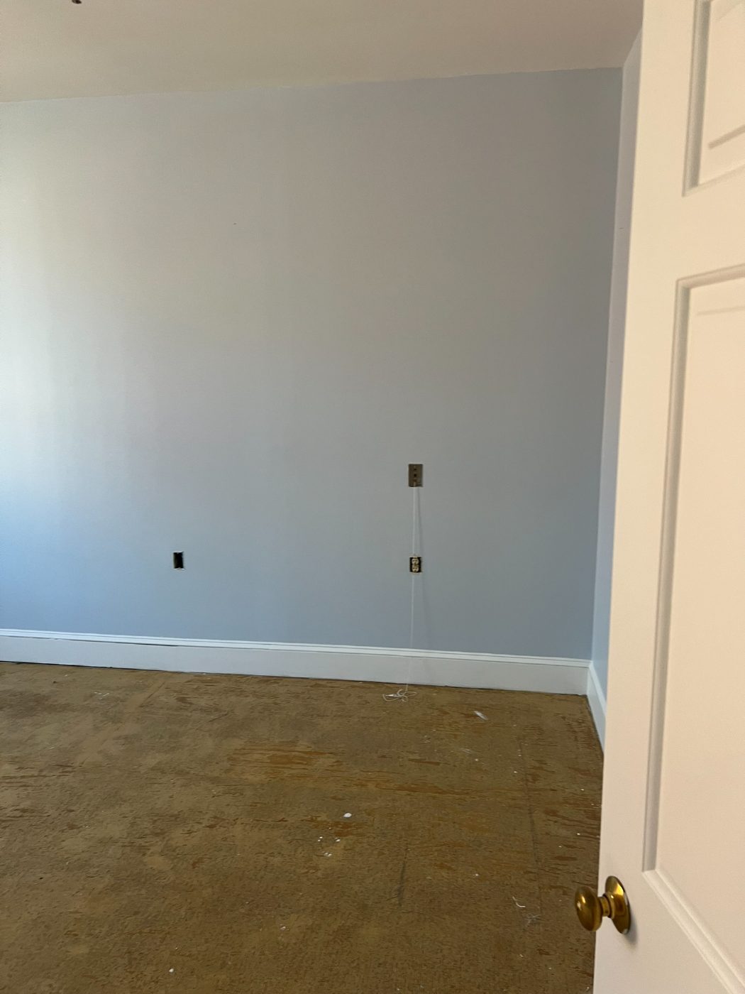 Corner of a light blue bedroom with smooth painted walls