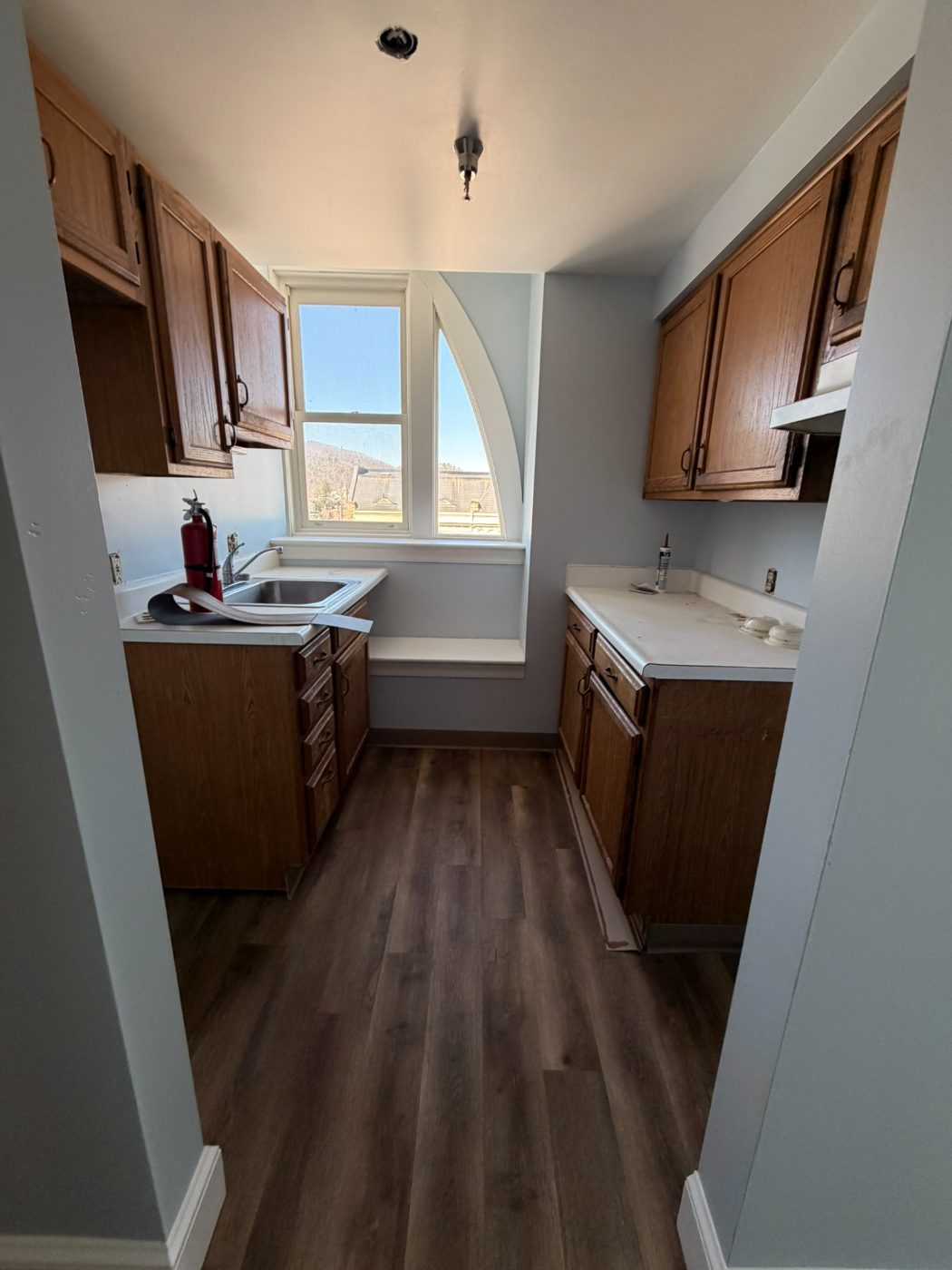 Galley kitchen with painted walls, wood cabinets and hardwood floors